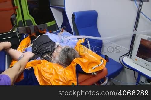 Paramedic provide medical care to obese senior patient in emergency ambulance measuring blood pressure