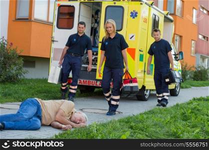 Paramedic team arriving to unconscious senior man lying on street