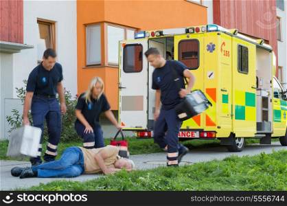 Paramedical team arriving to unconscious elderly man lying on street
