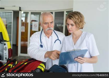 paramedics by ambulance looking at clipboard