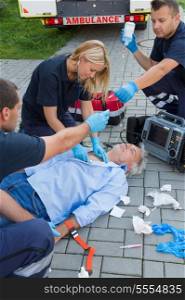 Paramedics examining unconscious senior man lying on ground
