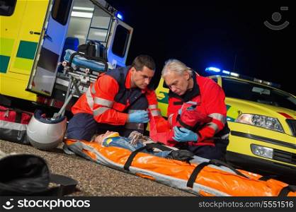 Paramedics giving firstaid to injured motorbike woman driver at night