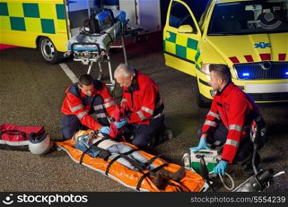 Paramedics helping injured woman motorbike driver on stretcher at night