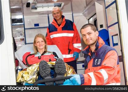 Paramedics helping woman on stretcher in ambulance smiling accident victim