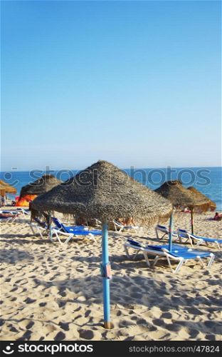 parasols and sun loungers on the beach on Faro island, Algarve. Portugal