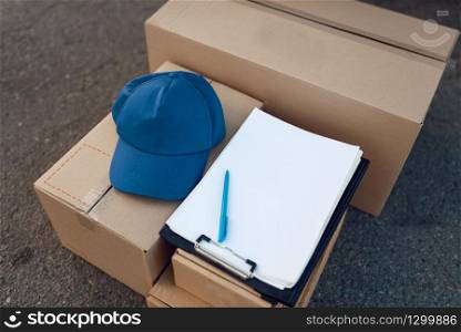 Parcel boxes and cap with notebook, delivery service concept, delivering business, nobody. Cardboard packages, deliver, courier or shipping job