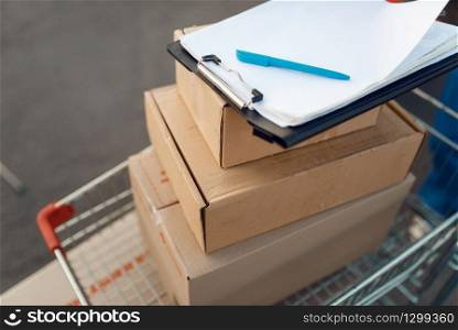 Parcel boxes and notebook in cargo cart, delivery service concept, delivering business, nobody. Cardboard packages, deliver, courier or shipping job