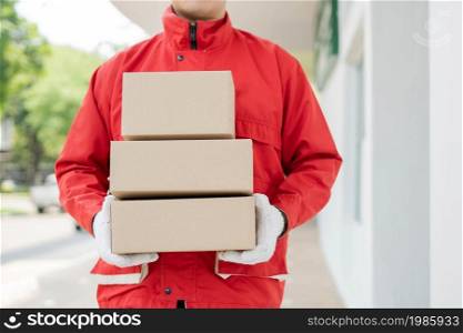 Parcel delivery concept the mailman standing, holding three boxes of parcels, and waiting to distribute them to the customers.