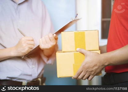 parcel delivery man of a package through a service. and close up hand customer accepting a delivery of boxes from delivery man postal send direct to home.