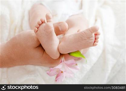 Parent holding in the hands feet of newborn baby. Tiny newborn baby&rsquo;s feet on hands closeup. Mom and her child. Happy Family concept. Beautiful conceptual image of maternity.