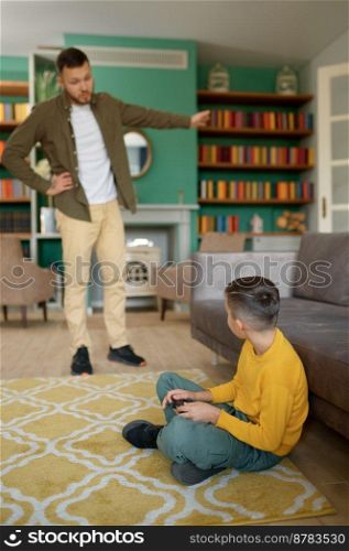 Parent scolding child addicted to modern technologies at home. Father forcing son go for walk instead of watching or playing games on smartphone. Parent scolding child addicted to modern technologies at home