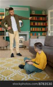 Parent scolding child addicted to modern technologies at home. Father forcing son go for walk instead of watching or playing games on smartphone. Parent scolding child addicted to modern technologies at home