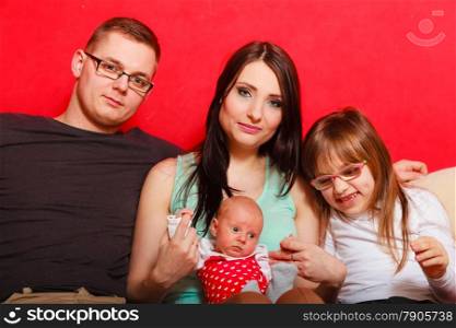 Parenthood and happiness concept. Young family mother father and child preschooler sitting on sofa with newborn baby girl at home