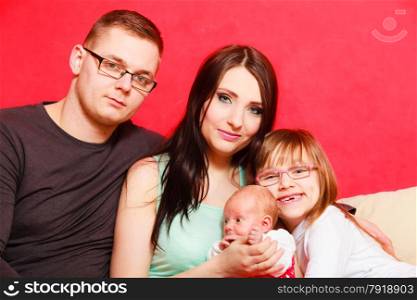 Parenthood and happiness concept. Young family mother father and child preschooler sitting on sofa with newborn baby girl at home