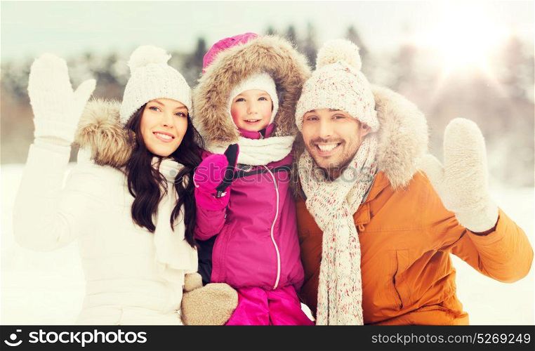 parenthood, fashion, gesture, season and people concept - happy family with child in winter clothes waving hands outdoors. happy family waving hands outdoors in winter