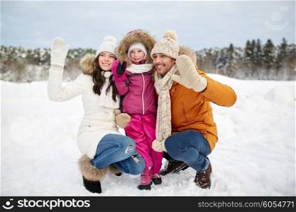 parenthood, fashion, gesture, season and people concept - happy family with child in winter clothes waving hands outdoors
