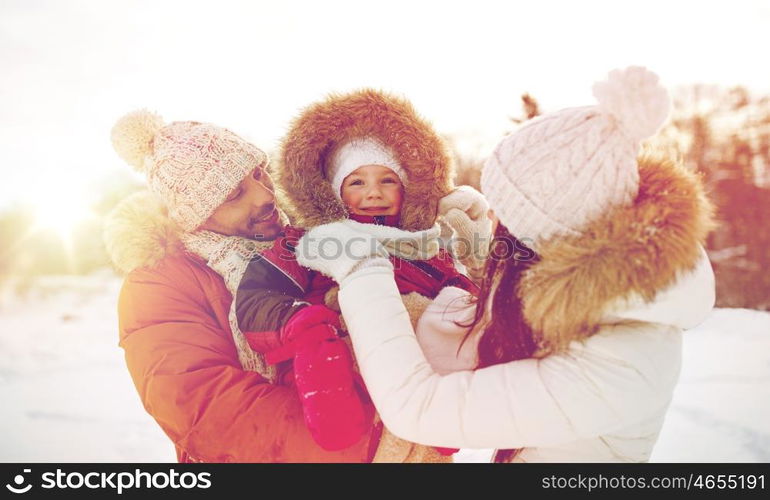 parenthood, fashion, season and people concept - happy family with child in winter clothes outdoors