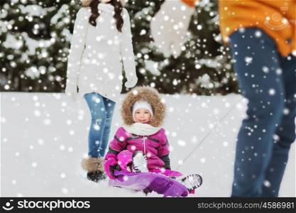 parenthood, fashion, season and people concept - happy family with child on sled walking in winter forest