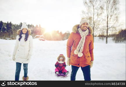 parenthood, fashion, season and people concept - happy family with child on sled walking in winter outdoors