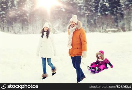 parenthood, fashion, season and people concept - happy family with child on sled walking in winter forest. happy family with sled walking in winter forest