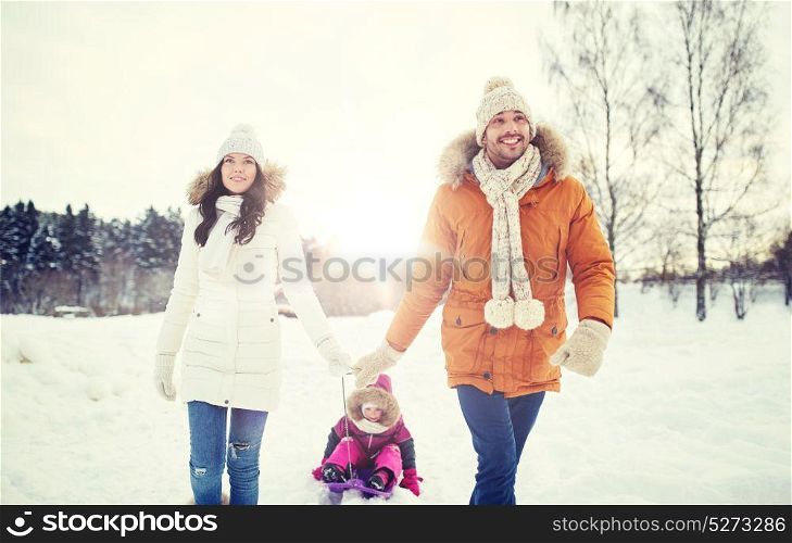 parenthood, fashion, season and people concept - happy family with child on sled walking in winter outdoors. happy family with sled walking in winter outdoors