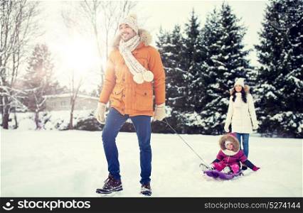 parenthood, fashion, season and people concept - happy family with child on sled walking in winter outdoors. happy family with sled walking in winter outdoors