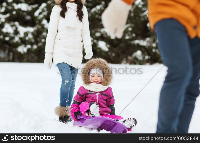 parenthood, fashion, season and people concept - happy family with child on sled walking in winter forest