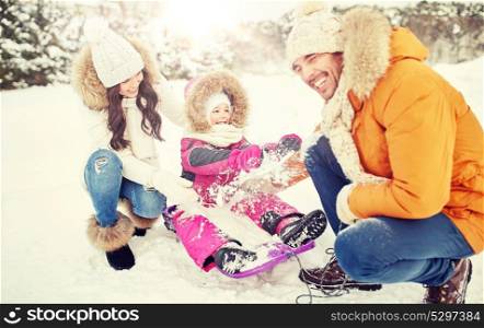 parenthood, fashion, season and people concept - happy family with child on sled having fun outdoors. happy family with kid on sled having fun outdoors