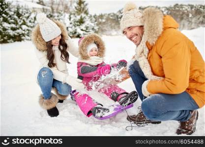 parenthood, fashion, season and people concept - happy family with child on sled having fun outdoors