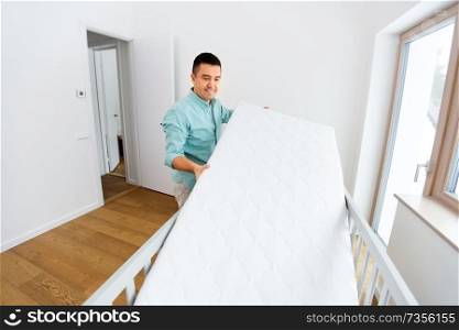 parenthood, fatherhood and nursery concept - middle-aged father arranging baby bed with mattress at home. father arranging baby bed with mattress at home