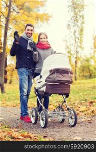 parenthood, gesture, family, season and people concept - smiling couple with baby pram waving hands in autumn park