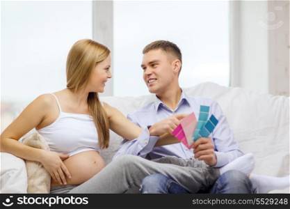 parenthood, renovation and pregnancy concept - smiling expecting parents choosing color for nursery