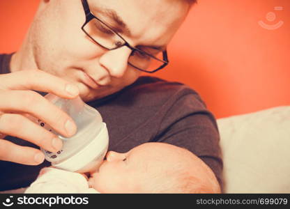 Parenting and love concept. Father holding and taking care of little newborn baby, feeding milk from bottle.. Father feeding from bottle newborn baby