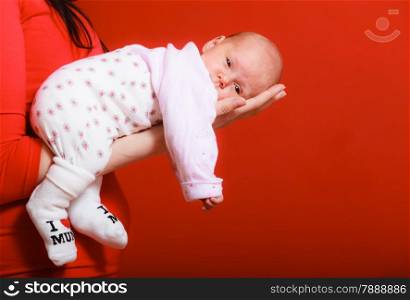 Parenting and love concept. one month old baby girl in the comfort of moms arms, red background