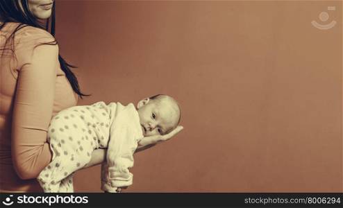 Parenting and love concept. one month old baby girl in the comfort of moms arms filtered photo