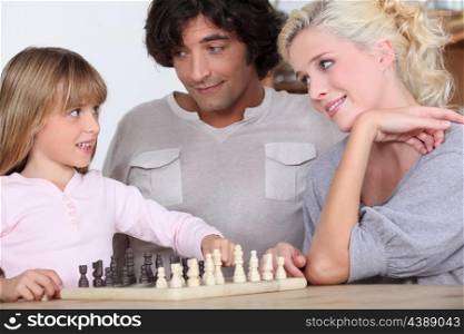 Parents and daughter playing chess