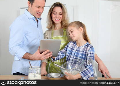 Parents and daughter preparing meal in home kitchen