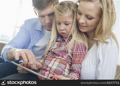 Parents and daughter using tablet computer in living room