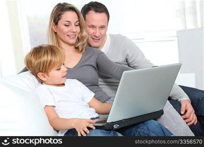 Parents and little boy at home with laptop computer