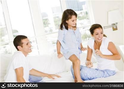 Parents and their daughter sitting on the bed