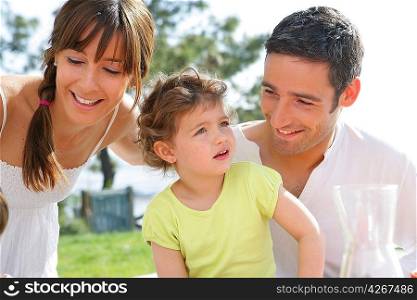 parents and their little girl having picnic in the park