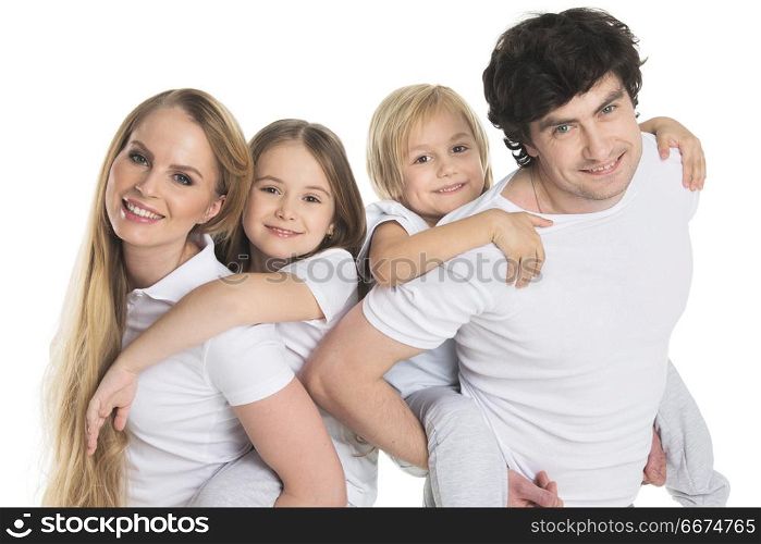 Parents and two children. Parents giving two children piggyback rides smiling isolated on white background