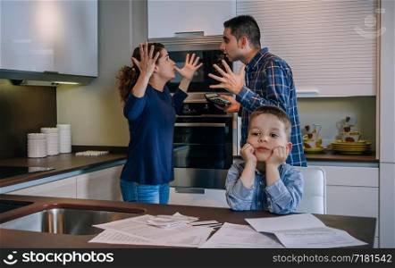 Parents arguing heatedly in the kitchen with their little son in front. Parents arguing with their little son in front