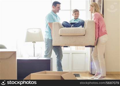 Parents carrying son on armchair in new house