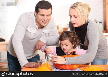 Parents carving a pumpkin with their daughter