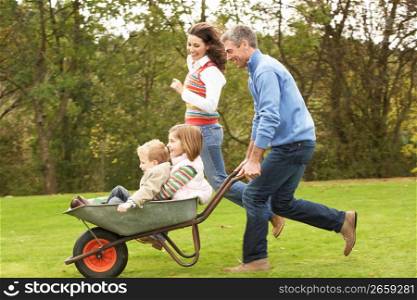 Parents Giving Children Ride In Wheelbarrow