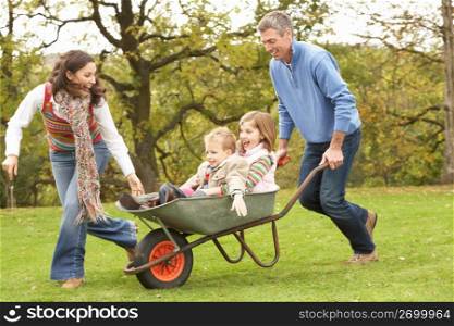 Parents Giving Children Ride In Wheelbarrow