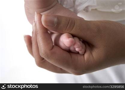Parents Hand Holding Little Baby Foot In The Studio