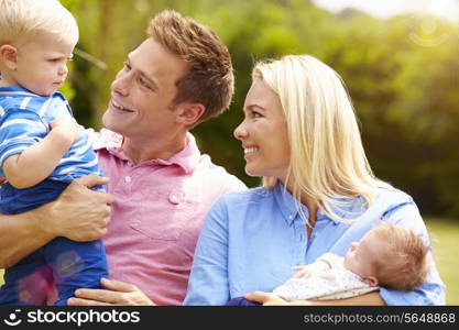 Parents Holding Young Children In Garden