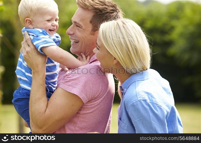 Parents Hugging Young Son In Garden